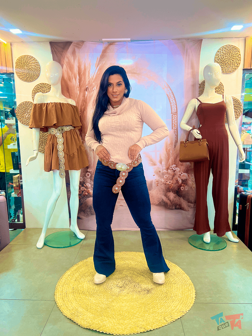 Look jeans flare com blusa bege claro e cinto com fivela trabalhada.